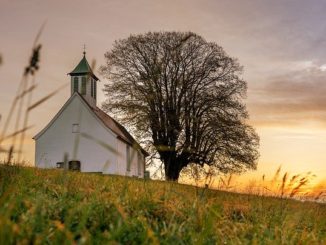 Kirche auf einem Feld bei Sonnenuntergang: Kirchenbanken unterstützen vor allem kirchliche und karitative Einrichtungen finanziell