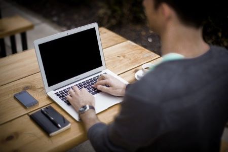 Junger Mann am Laptop: Wenn Sie einen 25000 Euro Kredit benötigen, können Sie diesen heutzutage ganz leicht online beantragen!