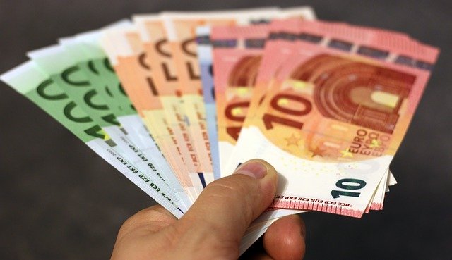 Linke Hand, die verschiedene Euro-Geldscheine hält: Wenn Sie schnell Geld benötigen, können Sie noch heute einen günstigen 5500 Euro Kredit online beantragen!