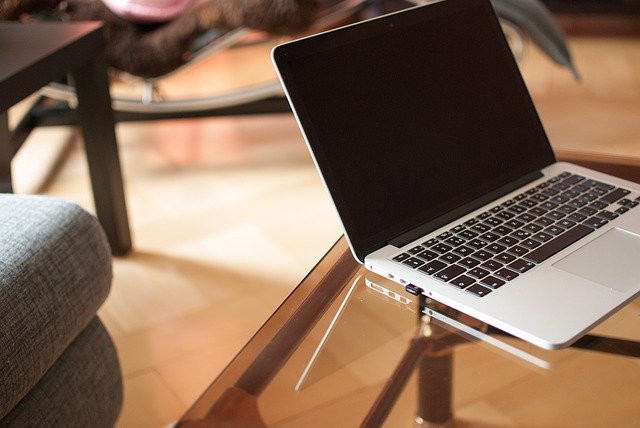 Laptop auf einem Glastisch: Wenn Sie einen Kredit iHv 65000 Euro benötigen, können Sie diesen heutzutage bequem online beantragen!