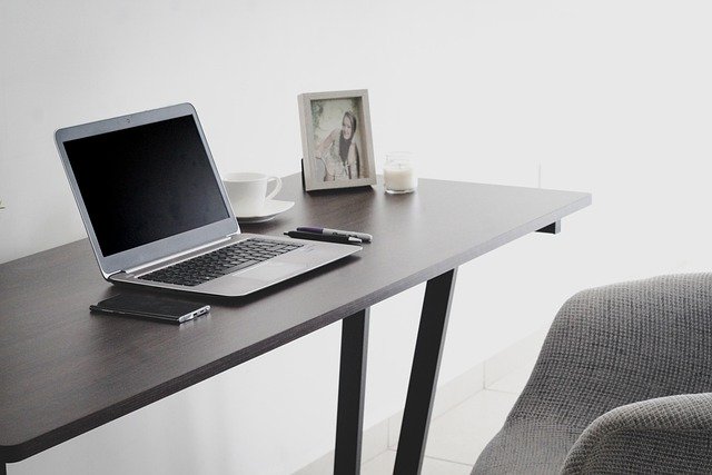 Smartphone, Laptop, Stift, Tasse Kaffee, weiße Kerze und Bild von einer Frau auf einem Schreibtisch: Wenn Sie schnellstmöglich einen Kredit für private Zwecke benötigen, können Sie noch heute bequem online den Barclaycard Ratenkredit beantragen! 