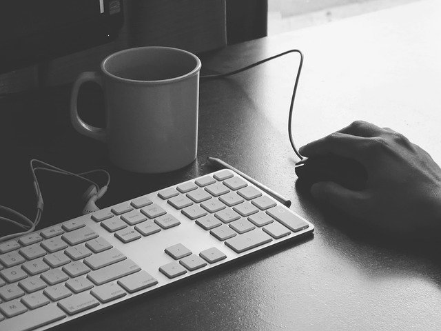 Tastatur, Tasse und Maus, die von einer Hand geführt wird, auf einem Bürotisch: Wenn Sie einen günstigen Ratenkredit mit Sofortauszahlung benötigen, dann können Sie noch heute den flexiblen Creditplus Kredit online beantragen!