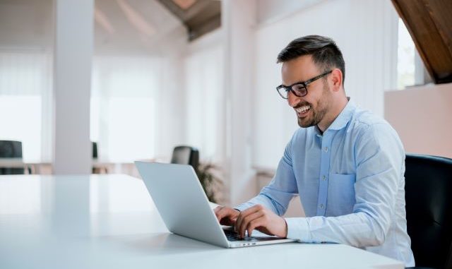 Junger Mann im Business-Hemd am Laptop sitzend: Die Digitalisierung hat es möglich gemacht, einen Kredit online unterschreiben und aufnehmen zu können - mit Hilfe der digitalen Unterschrift!